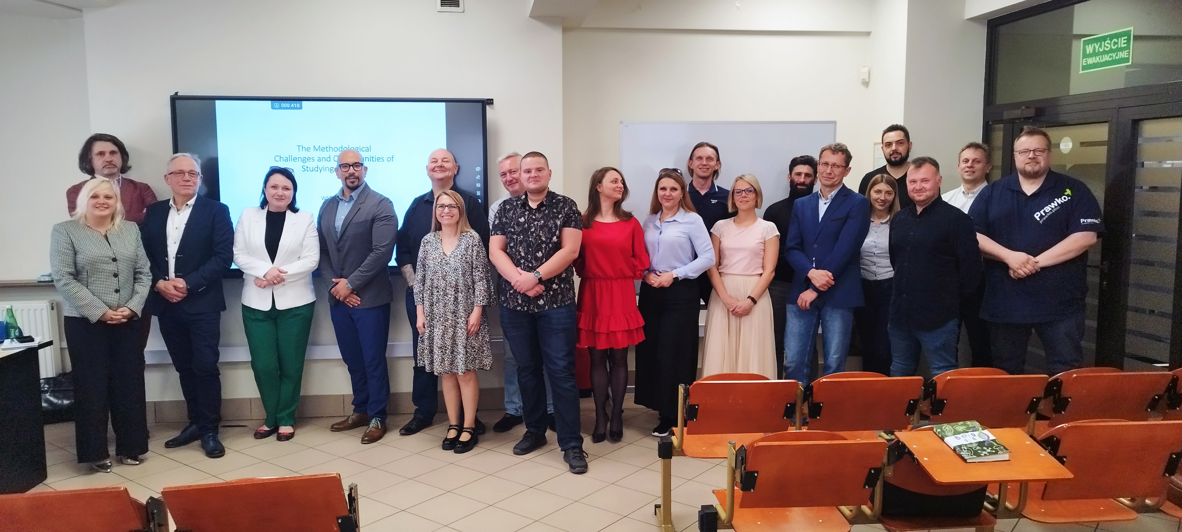 Grupa osób pozująca do zdjęcia w sali wykładowej podczas wydarzenia.