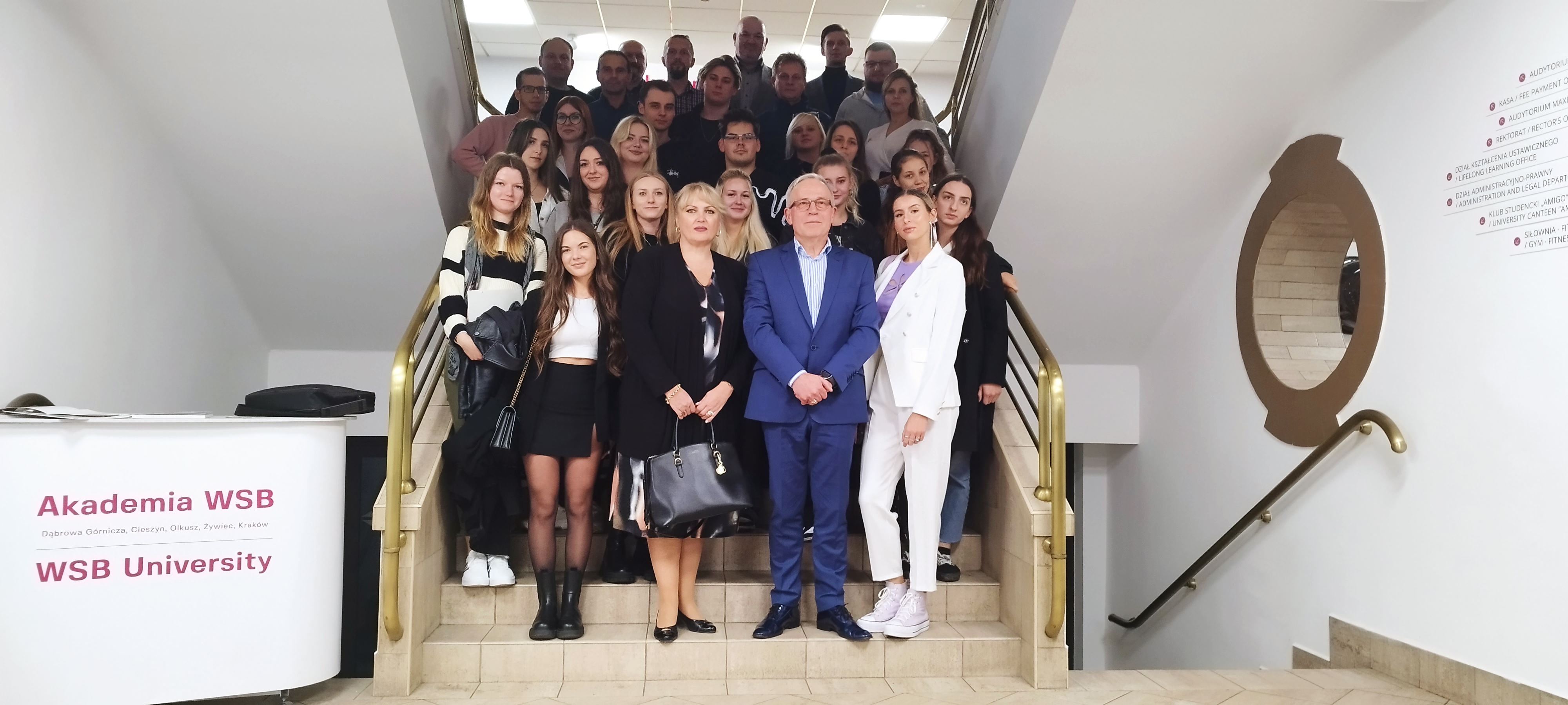 Grupa osób pozującą na schodach w Akademii WSB.