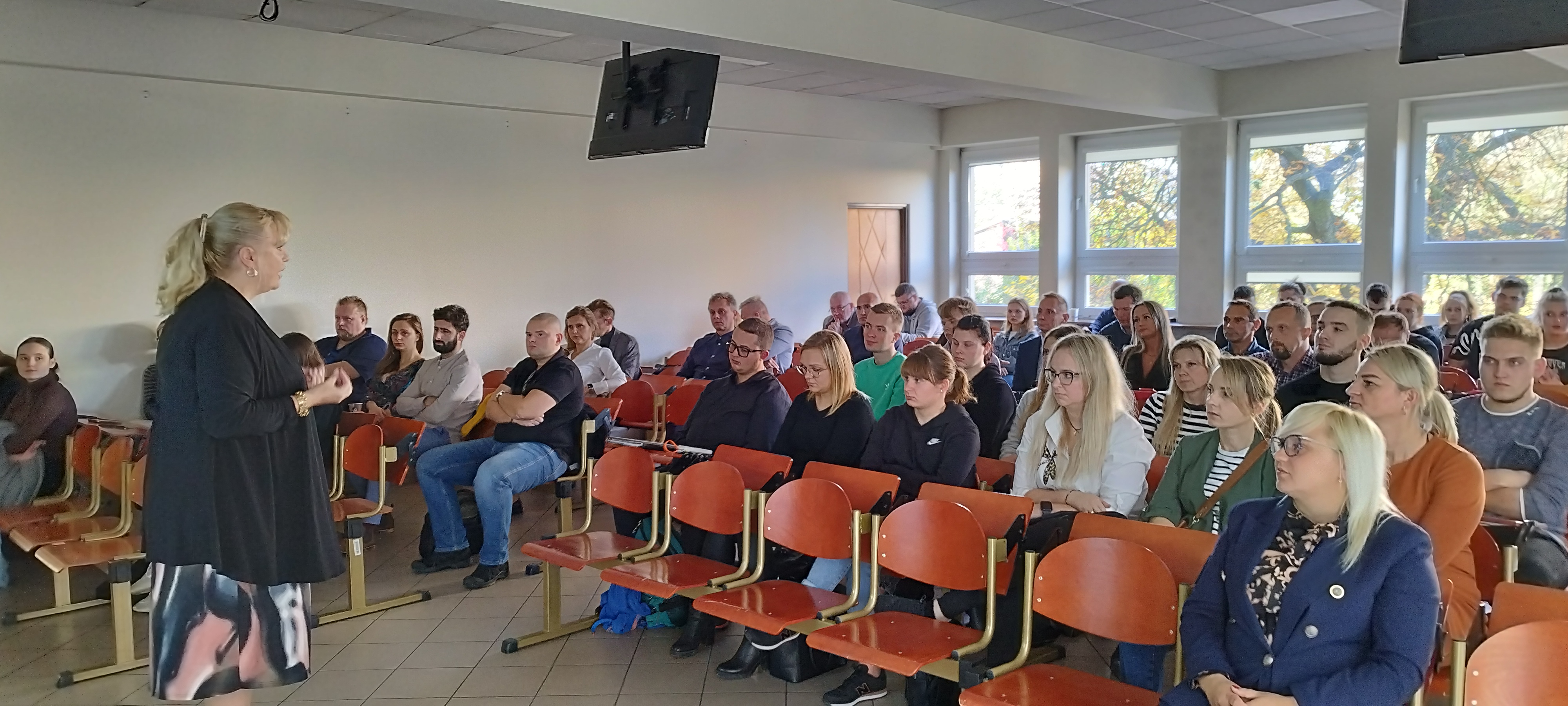 Osoby słuchające prelegenta podczas wykładu w sali wykładowej.